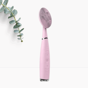 Rosa elektrisches Gesichtsreinigungsgerät mit Silikonbürste, daneben dekorativer Eukalyptuszweig.