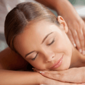 Eine Frau liegt entspannt mit geschlossenen Augen auf der Massagebank, während ihre Schultern sanft massiert werden. Das Bild vermittelt Ruhe, Wärme und Entspannung während einer professionellen Rückenmassage in Gütersloh.